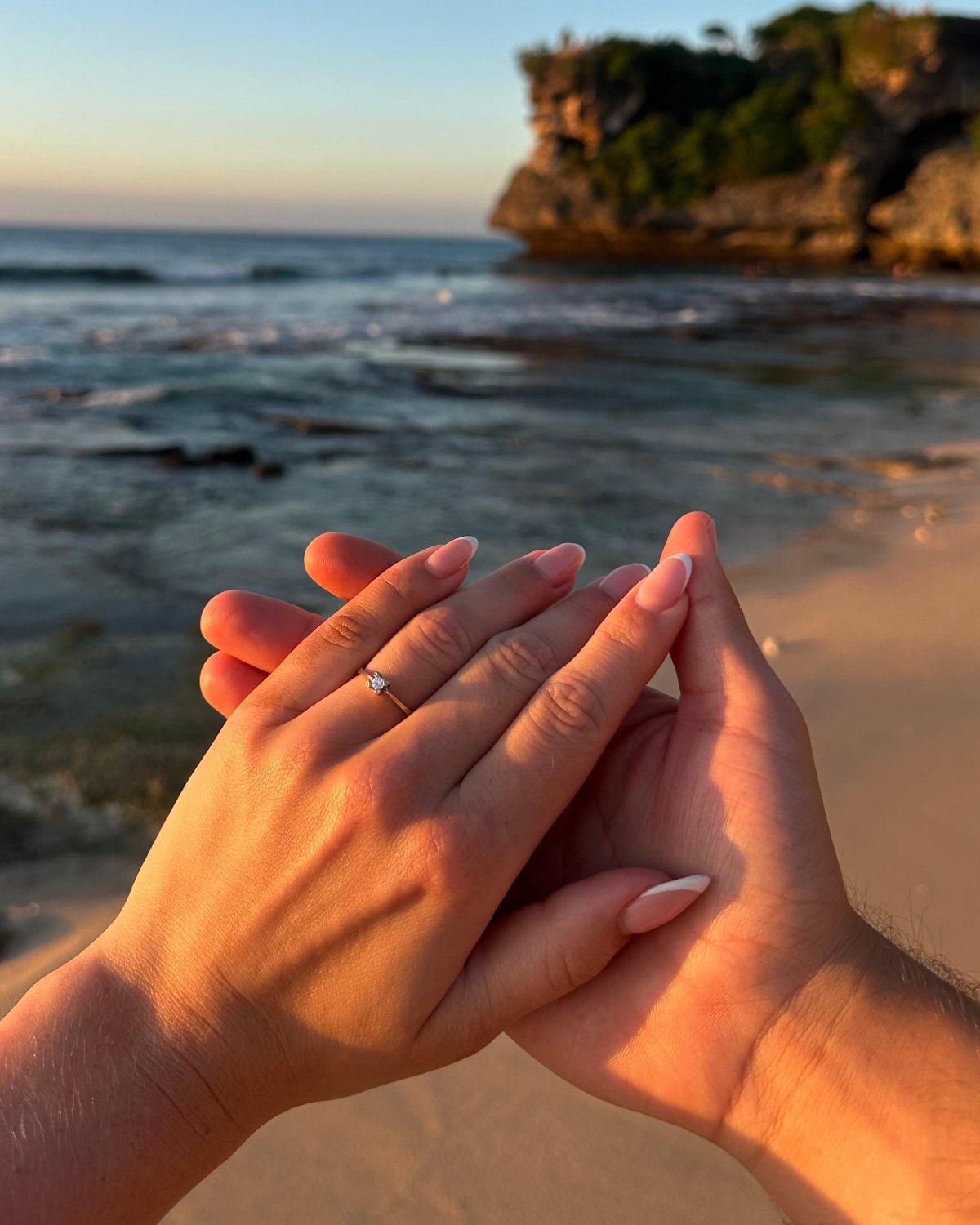Hände mit Verlobungsring vor dem Meer